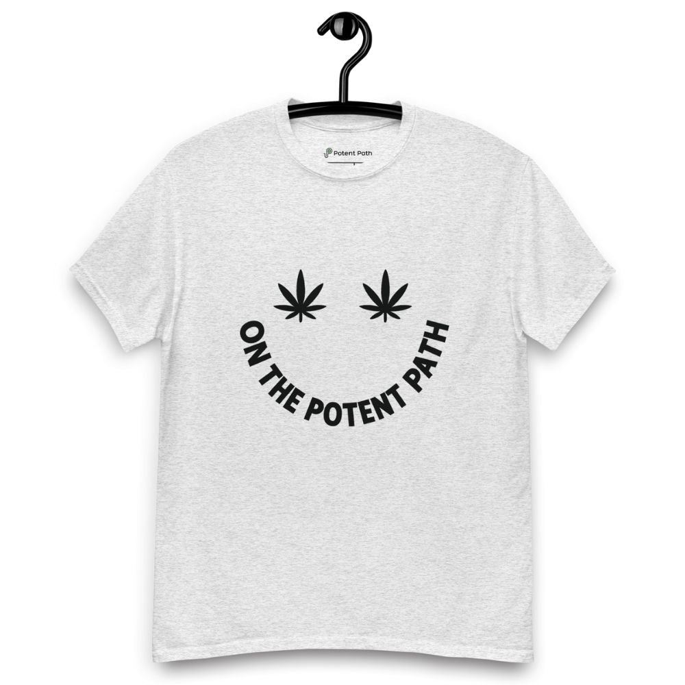 Ash grey colour t-shirt on a hanger featuring curved text reading "ON THE POTENT PATH" in the form of a smiley face and two black cannabis leaves above to represent the eyes