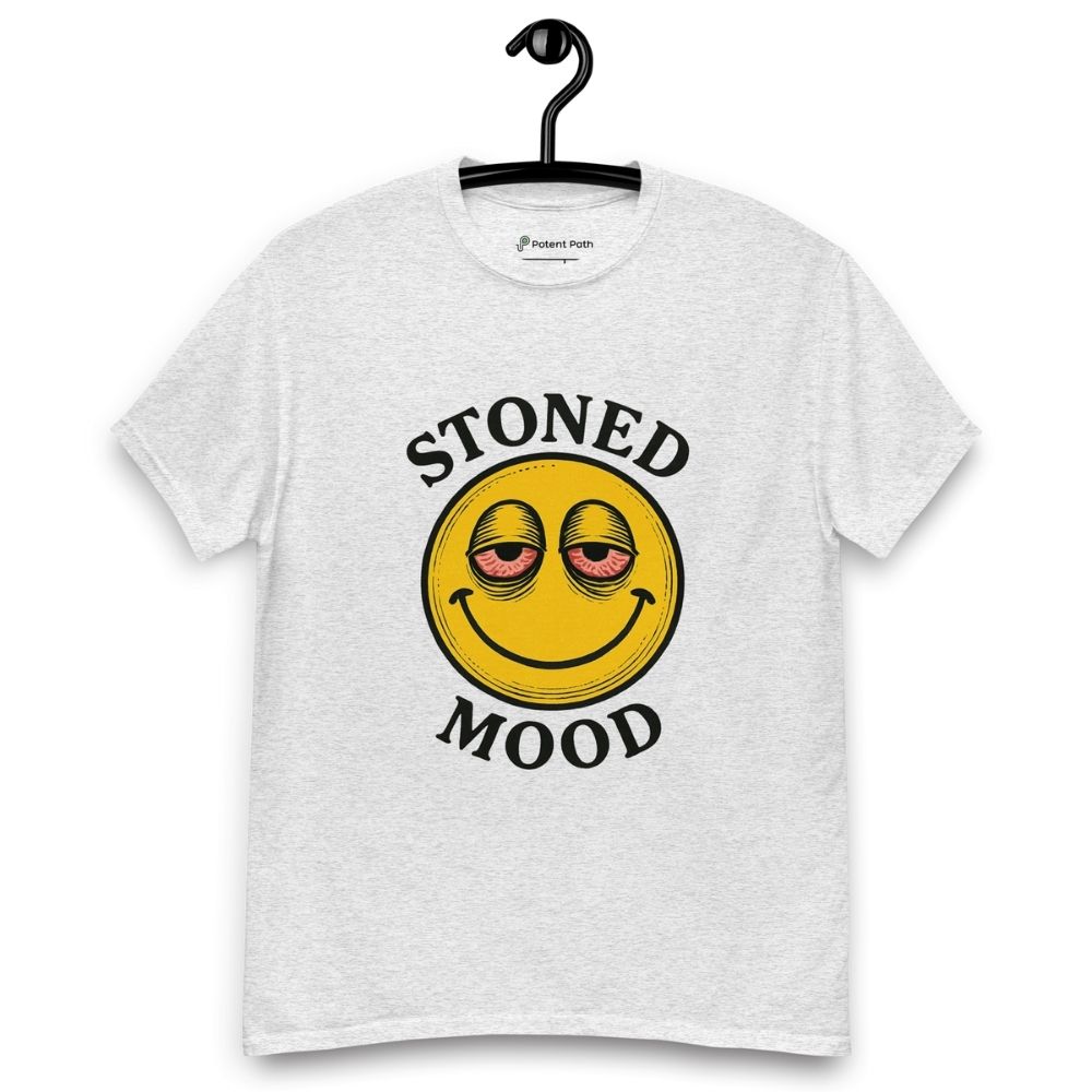 Ash grey colour T-shirt on a hanger with a yellow smiley face with droopy, bloodshot eyes and the phrase "STONED MOOD" printed above and below the graphic