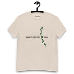 Beige t-shirt on a hanger featuring the phrase "Walking The Potent Path Slowly" in white text across the chest, with a vertical trail of small green footprints with cannabis leaves inside between "Path" and "Slowly"