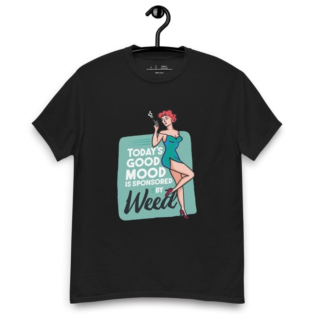 Black T-shirt on a hanger featuring a retro-style illustration of a woman in a teal dress holding a smoking joint, next to the text “TODAY'S GOOD MOOD IS SPONSORED BY Weed"