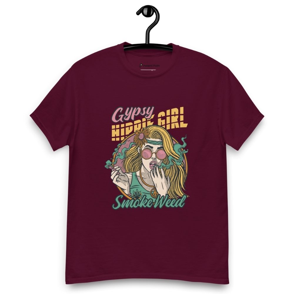 Burgundy T-shirt on a hanger featuring a colourful illustration of a woman with long blonde hair, round pink sunglasses, and a flower in her hair, smoking weed with swirling smoke around her and text "Gypsy Hippie Girl" above and "Smoke Weed" below