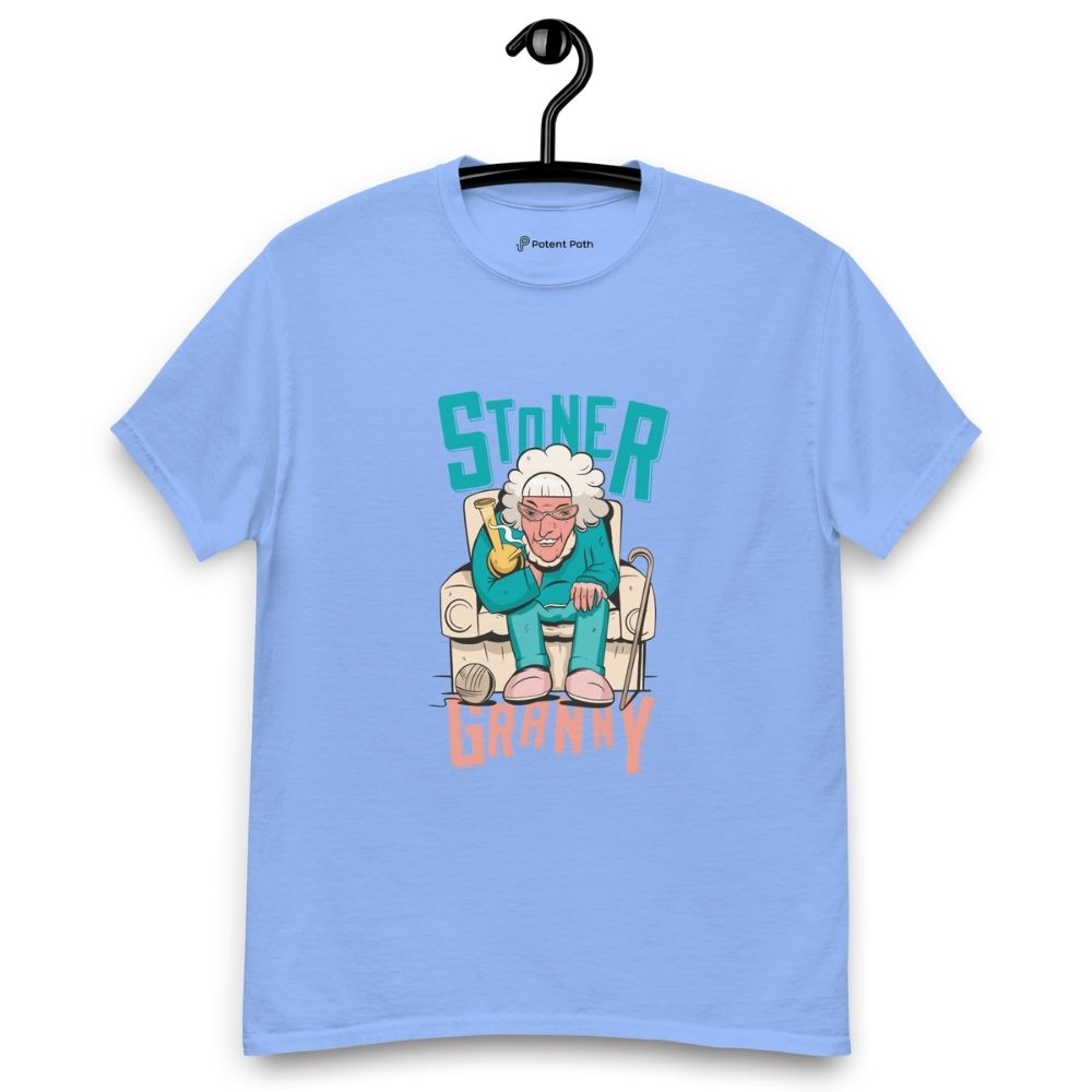 Caroline blue T-shirt on a hanger featuring a cartoon illustration of an elderly woman in a teal tracksuit sitting in an armchair, holding a yellow bong, with the text "STONER GRANNY" above and below her.