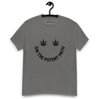 Charcoal grey t-shirt on a hanger featuring curved text reading "ON THE POTENT PATH" in the form of a smiley face and two black cannabis leaves above to represent the eyes