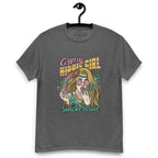 Dark heather T-shirt on a hanger featuring a colourful illustration of a woman with long blonde hair, round pink sunglasses, and a flower in her hair, smoking weed with swirling smoke around her and text "Gypsy Hippie Girl" above and "Smoke Weed" below
