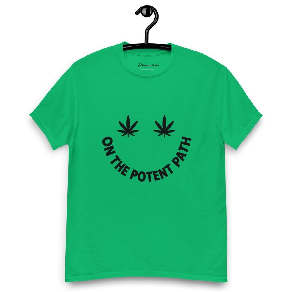 Green t-shirt on a hanger featuring curved text reading "ON THE POTENT PATH" in the form of a smiley face and two black cannabis leaves above to represent the eyes