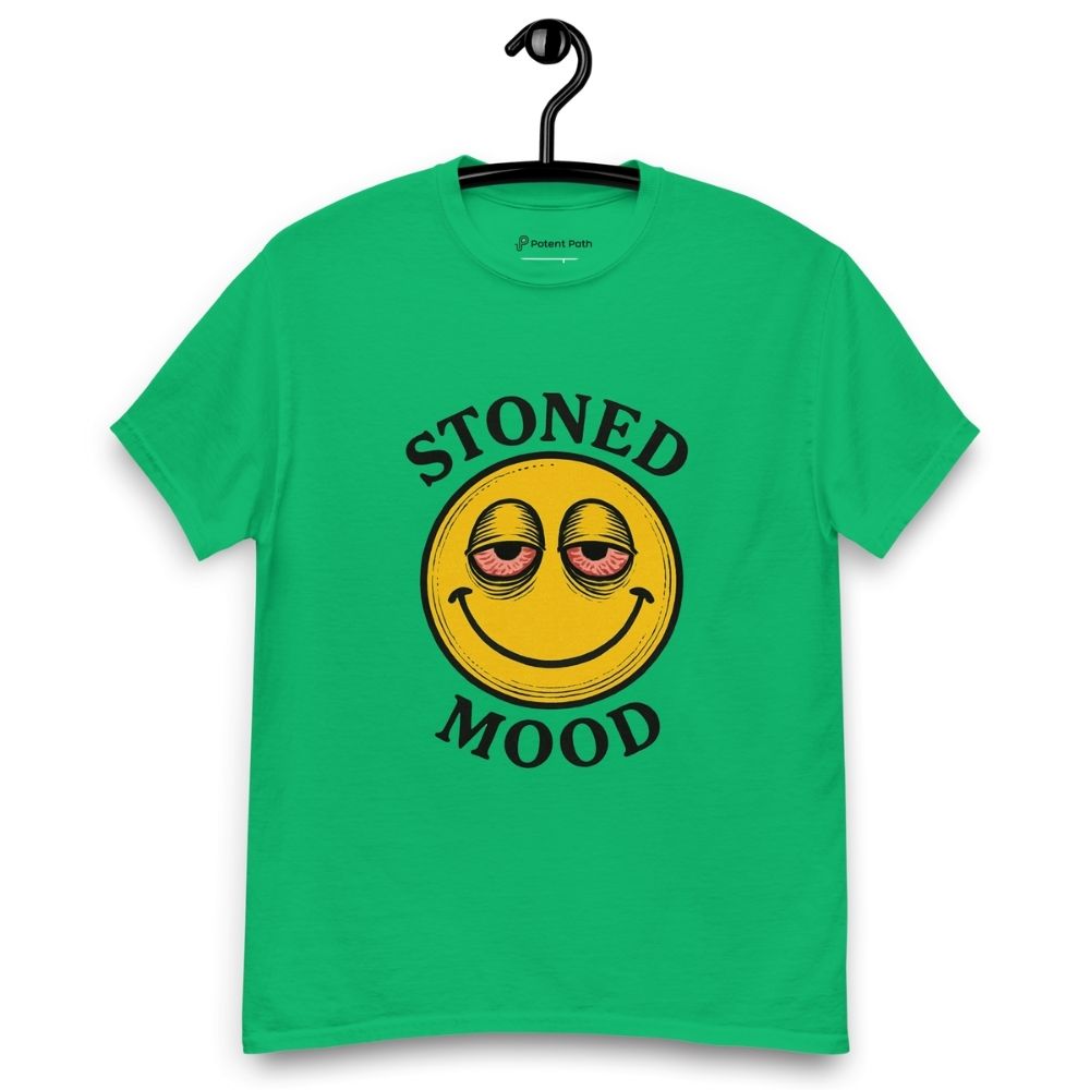 Green T-shirt on a hanger with a yellow smiley face with droopy, bloodshot eyes and the phrase "STONED MOOD" printed above and below the graphic