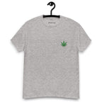 Grey t-shirt with a green cannabis leaf logo on a hanger against a white background