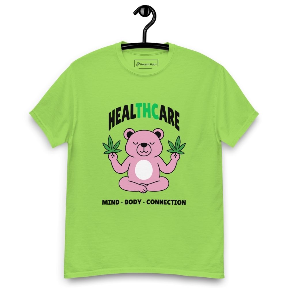 Lime green T-shirt on a hanger featuring a pink cartoon bear sitting in a meditative pose and holding two cannabis leaves, with the word "HEALTHCARE" above, with the words "THC" highlighted in green and the phrase "MIND, BODY, CONNECTION" below