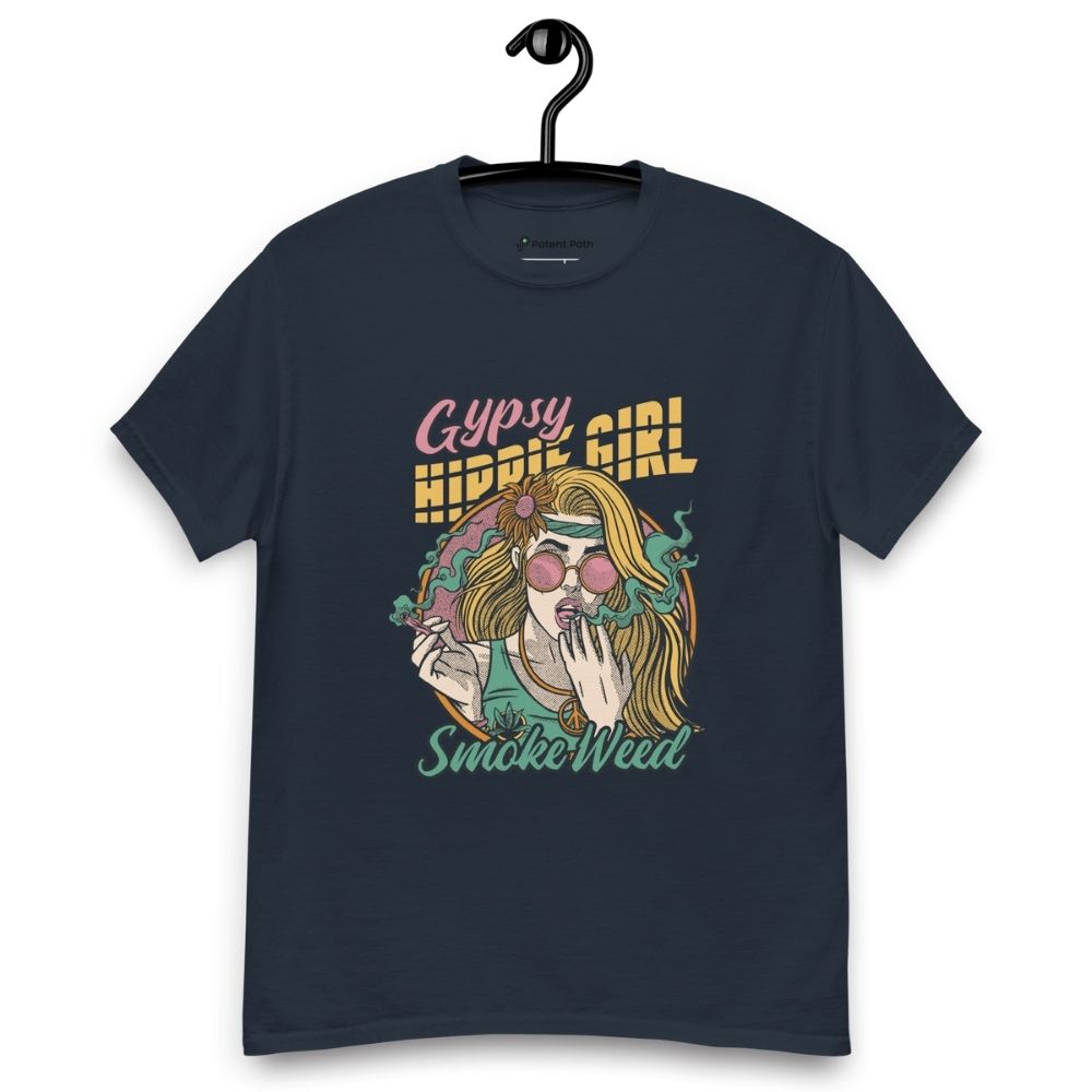 Navy blue T-shirt on a hanger featuring a colourful illustration of a woman with long blonde hair, round pink sunglasses, and a flower in her hair, smoking weed with swirling smoke around her and text "Gypsy Hippie Girl" above and "Smoke Weed" below