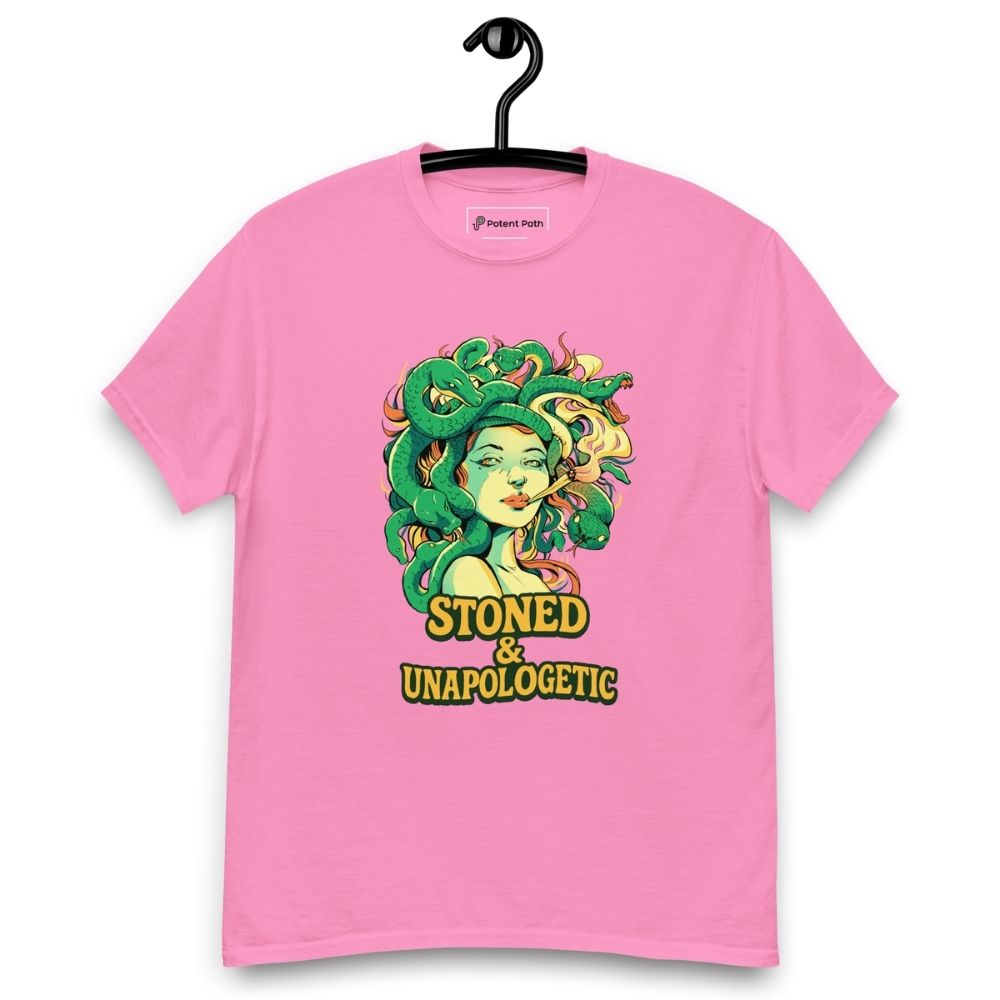 Pink T-shirt on a hanger featuring a Medusa head smoking a joint with green snake hair, and the text "STONED & UNAPOLOGETIC" below