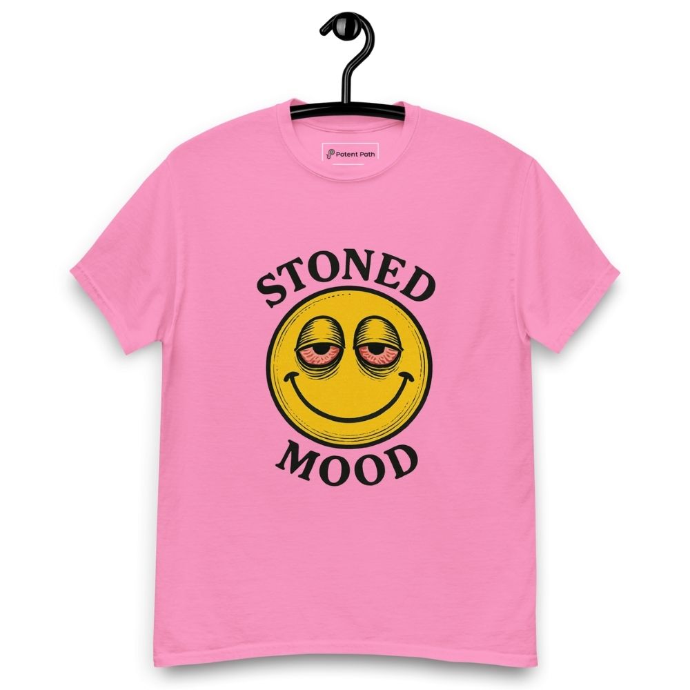 Pink T-shirt on a hanger with a yellow smiley face with droopy, bloodshot eyes and the phrase "STONED MOOD" printed above and below the graphic