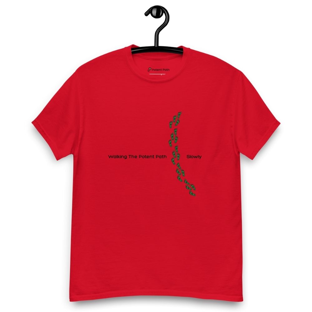Red t-shirt on a hanger featuring the phrase "Walking The Potent Path Slowly" in white text across the chest, with a vertical trail of small green footprints with cannabis leaves inside between "Path" and "Slowly"