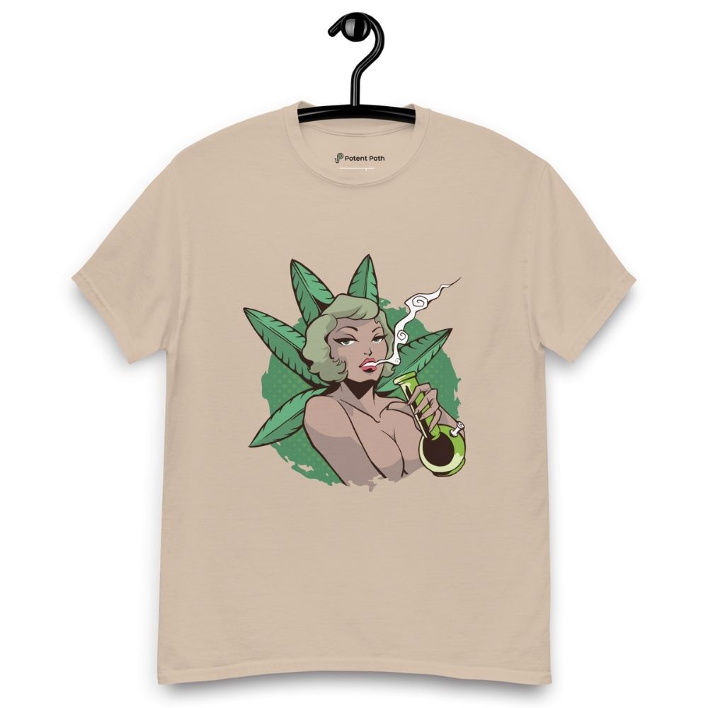 Sandy colour T-shirt on a hanger featuring a graphic on the chest of a pin-up style woman smoking a joint, framed by large green cannabis leaves