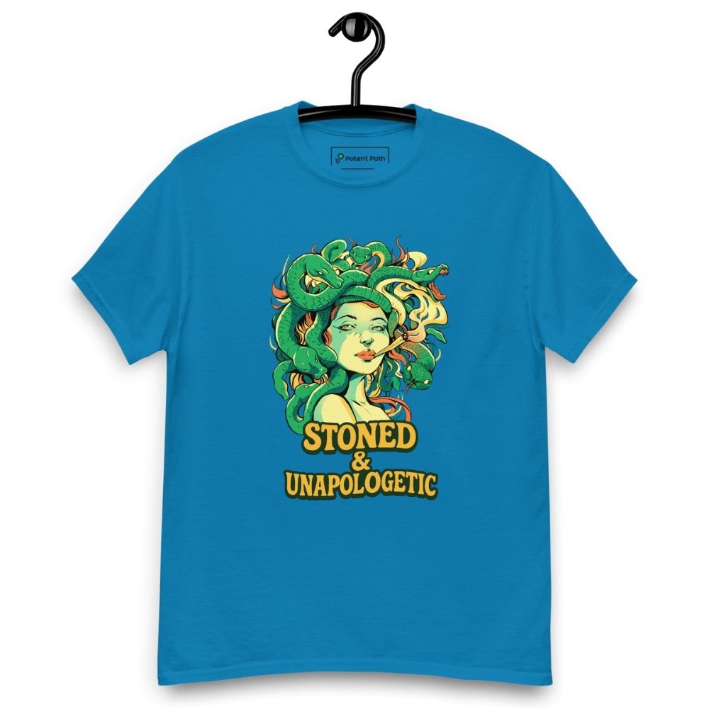 Sapphire blue T-shirt on a hanger featuring a Medusa head smoking a joint with green snake hair, and the text "STONED & UNAPOLOGETIC" below