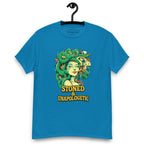 Sapphire blue T-shirt on a hanger featuring a Medusa head smoking a joint with green snake hair, and the text "STONED & UNAPOLOGETIC" below