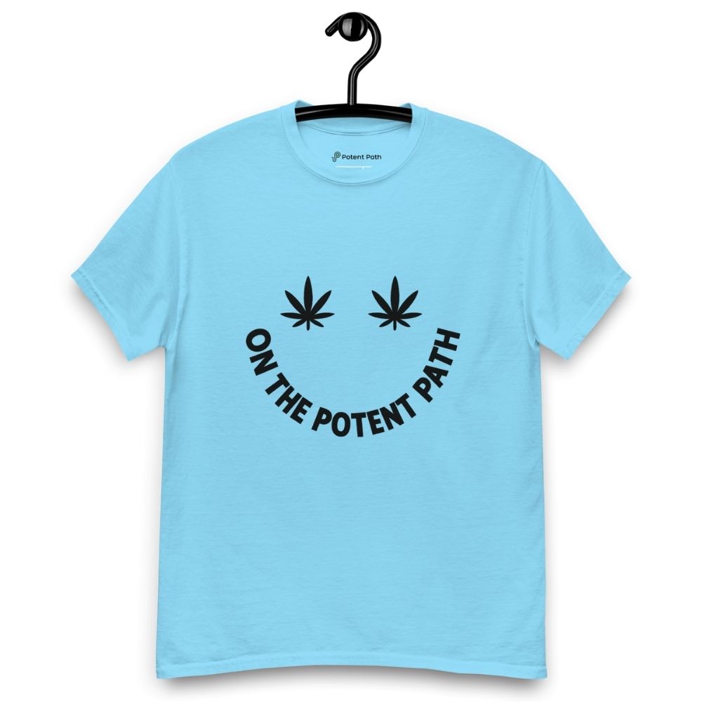 Sky blue t-shirt on a hanger featuring curved text reading "ON THE POTENT PATH" in the form of a smiley face and two black cannabis leaves above to represent the eyes