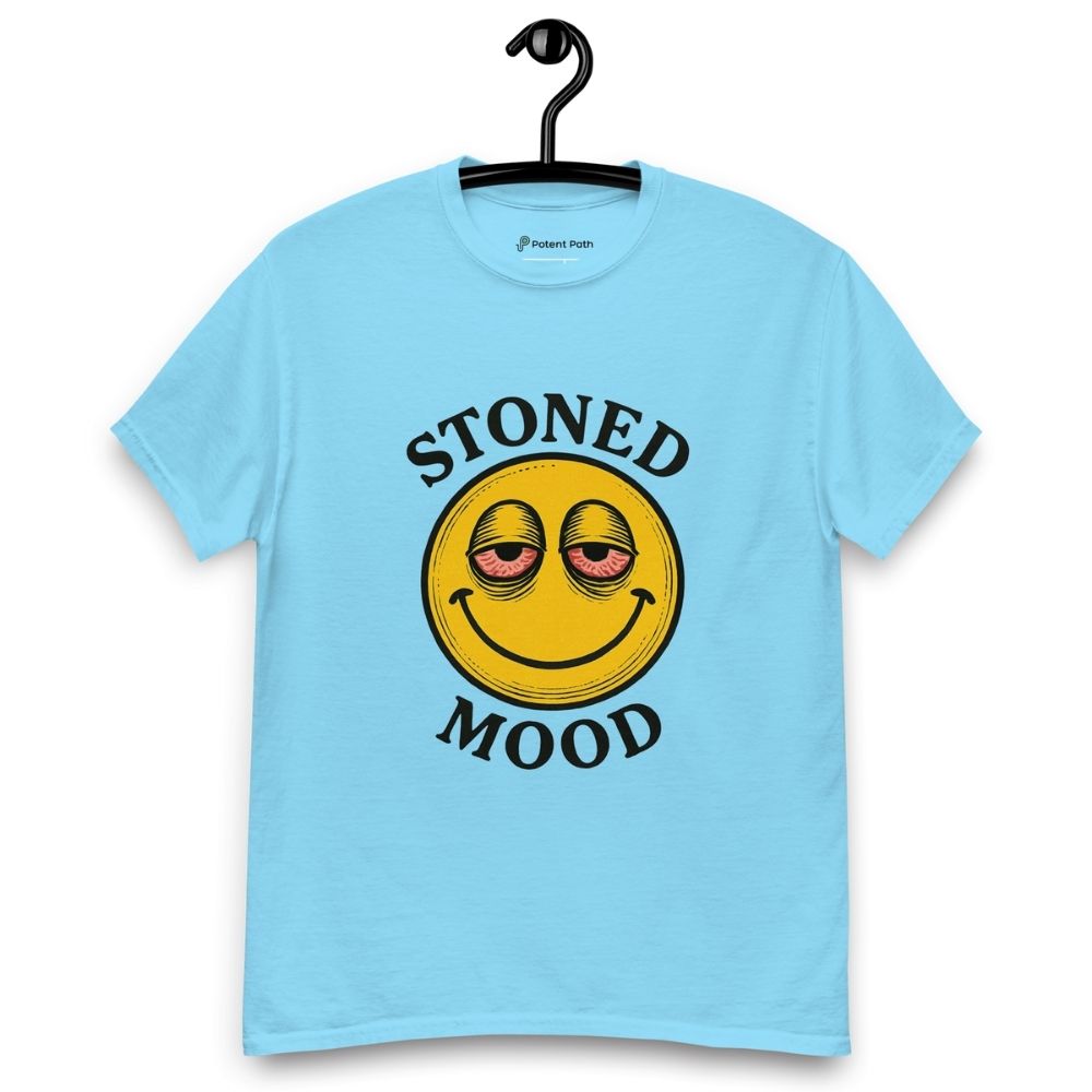 Light blue T-shirt on a hanger with a yellow smiley face with droopy, bloodshot eyes and the phrase "STONED MOOD" printed above and below the graphic