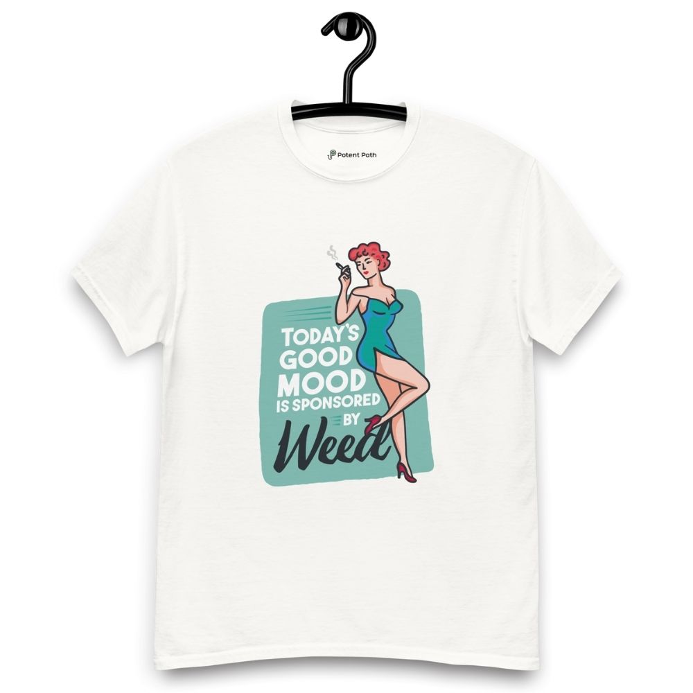 White T-shirt on a hanger featuring a retro-style illustration of a woman in a teal dress holding a smoking joint, next to the text “TODAY'S GOOD MOOD IS SPONSORED BY Weed"