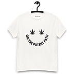 White t-shirt on a hanger featuring curved text reading "ON THE POTENT PATH" in the form of a smiley face and two black cannabis leaves above to represent the eyes