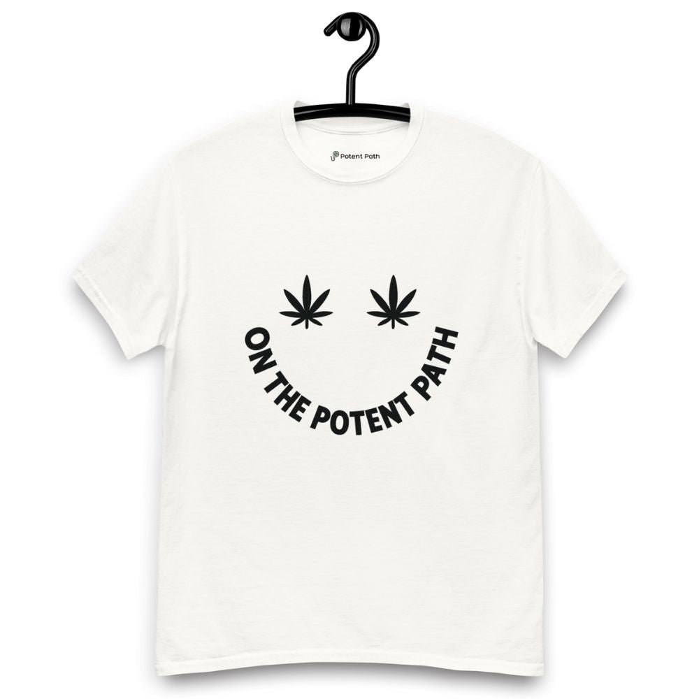 White t-shirt on a hanger featuring curved text reading "ON THE POTENT PATH" in the form of a smiley face and two black cannabis leaves above to represent the eyes
