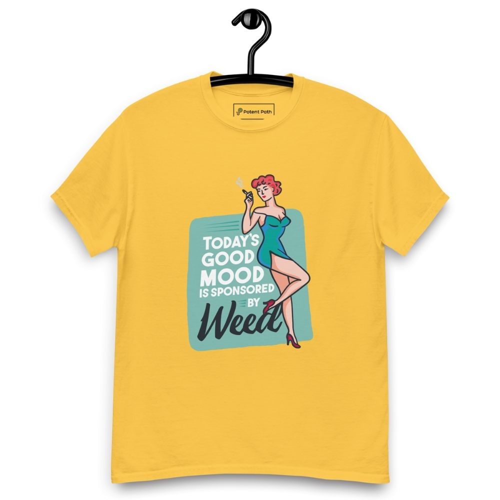 Yellow T-shirt on a hanger featuring a retro-style illustration of a woman in a teal dress holding a smoking joint, next to the text “TODAY'S GOOD MOOD IS SPONSORED BY Weed"